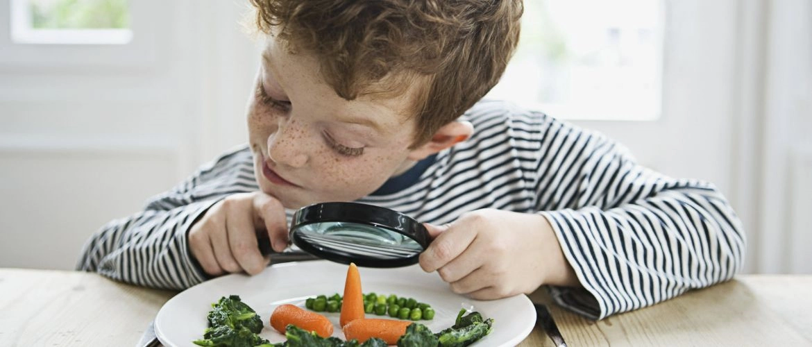 Chłopiec oglądający warzywa przez lupę