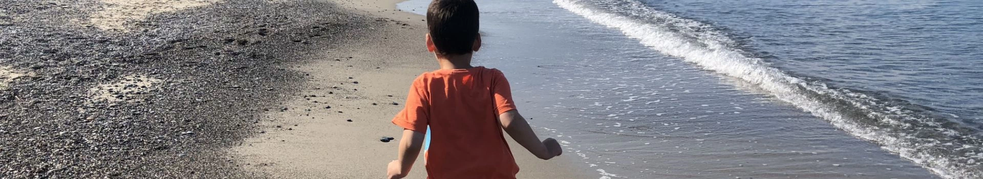 Chłopiec chodzący po plaży przy wodzie